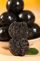 Black Sesame Balls Closeup - Handmade Nutritious Pure Sesame Seed Energy Balls with Mint Garnish on Wood Surface