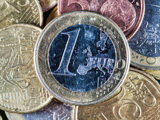 Pile of various euro coins close up background - A detailed close-up shot of a variety of euro coins, including 1 euro, 50 cent, 20 cent and others, piled together on a green surface.