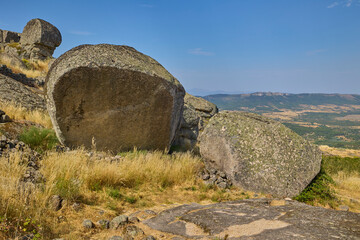 Large granite boulders and dry grass on a hilltop with mountains