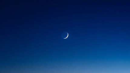 Crescent moon in clear night sky with deep blue hue and gradient