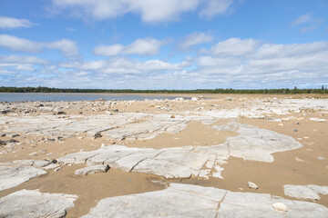 Rugged limestone shoreline at Misery Bay Provincial Park on Manitoulin Island, Ontario, under a blue sky.
