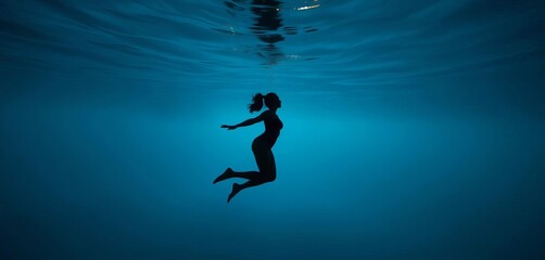 Naklejka premium Silhouette of a figure gracefully moving through a tranquil underwater scene, submerged, serene