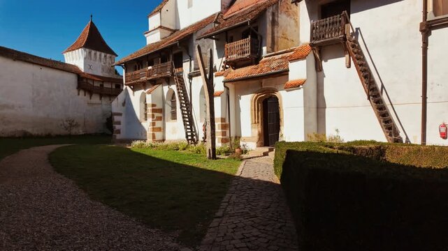 Harman Fortified Church, Harman, Transylvania, Romania, combines a white walled church, defensive ring, and robust tower, enclosing a calm courtyard that reflects centuries of community life