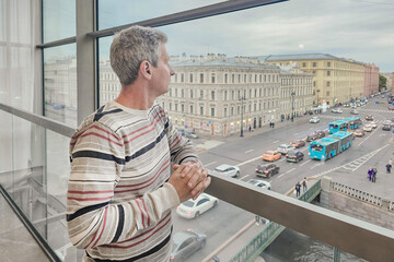 A man of 50+ stands at the window