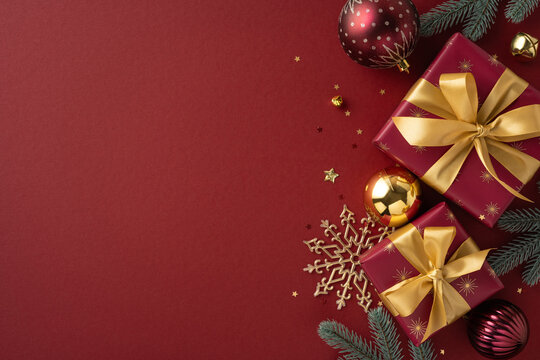 Christmas decor featuring wrapped gifts with golden ribbons, baubles, snowflakes, and evergreen branches on a vibrant red background