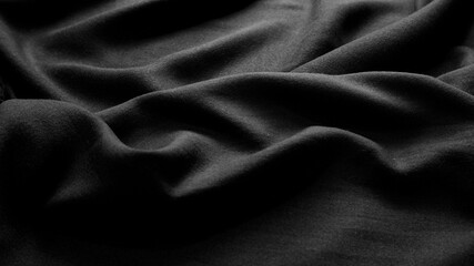 Black fabric texture background with soft rippled. Texture background of black clothing. Dark, wave, cotton, luxury, elegant, modern concept for wallpaper, cover, textiles. Close-up fabric surface.