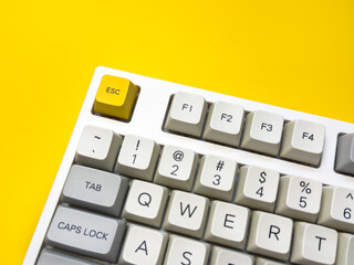 White mechanical keyboard with bright Esc key on bright yellow background, minimalism, keyboard...