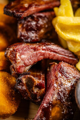 Close-up of smoked pork ribs with fries and nuggets