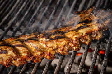 Grilled pork ribs cooking on barbecue with smoke
