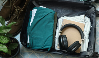 Close up of a person getting ready for travel and packing clothes into an open black suitcase, vacation travel concept. Person preparing for a trip and folding clothes into an open luggage.