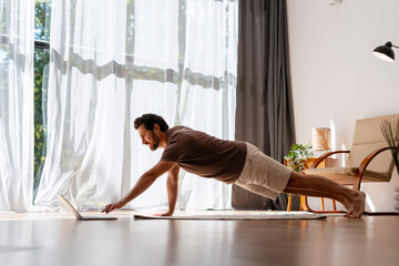 Man doing online workout at home using laptop computer