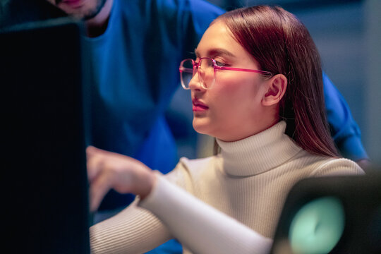 Asian programmers collaborating on software development at night, focused on writing code across multiple monitors in a tech office environment Programmers Collaborating on Software Development