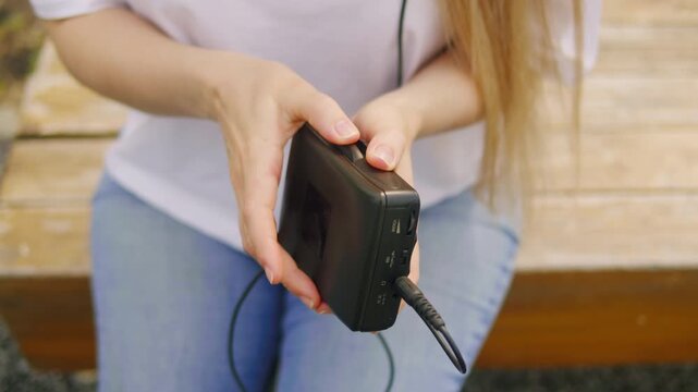 Vintage audio cassette tape playing music from cassette, used for portable music playback and recording, woman hands play cassette streaming, am fm radio from 90s.