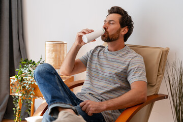 Man relaxing on armchair drinking yogurt