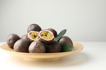 Fresh passion fruits with green leaves on white table