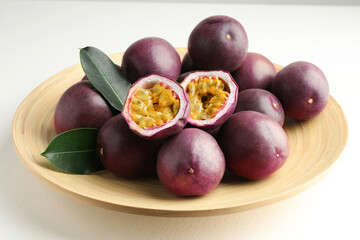 Fresh passion fruits with green leaves on white table