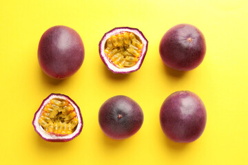 Fresh passion fruits on yellow background, flat lay. Whole and cut
