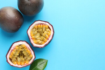 Fresh passion fruits with green leaf on light blue background, flat lay. Space for text