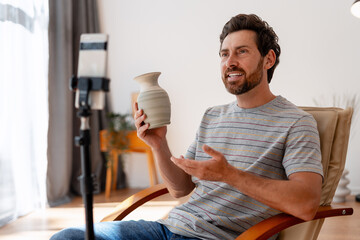 Ceramist vlogger presenting handmade vase during online workshop