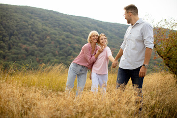 Fototapeta premium Family enjoying a joyful moment outdoors in a grassy field during autumn near mountains