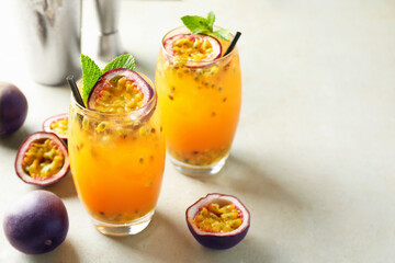 Tasty passion fruit drink with mint in glasses and fresh fruits on gray table, closeup. Space for text