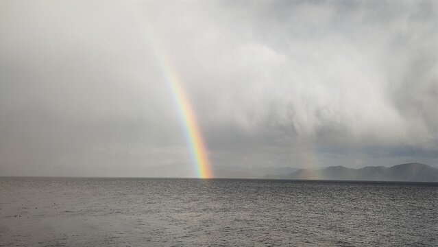 double rainbow arc above sea level ocean horizon dramatic sky weather