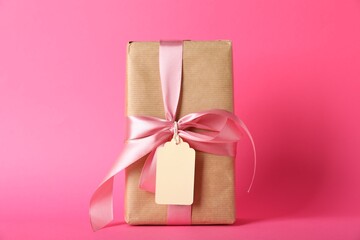 Gift box with blank tag on pink background