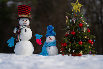 Funny snowman in snowy landscape. Snowman in winter holiday. Decorated snowman. Greeting card for New Year and Christmas poster. Family snowmen with snow background. Xmas winter banner.