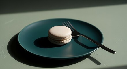 Solitary White Macaron on a Teal Plate with Dramatic Geometric Shadows.