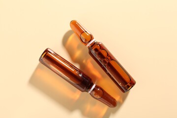 Glass ampoules with cosmetic product on beige background, flat lay