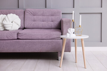 Comfortable sofa with cushions and decor on side table indoors