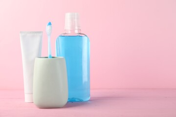 Mouthwash, toothpaste and toothbrush on pink background, space for text. Oral hygiene