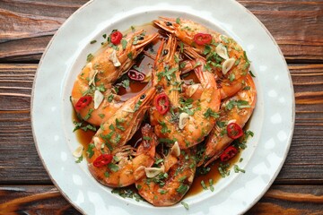 Tasty grilled shrimps with spices and sauce on wooden table, top view. Delicious seafood dish