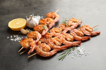 Skewers with tasty grilled shrimps and spices on grey table, closeup. Delicious seafood dish