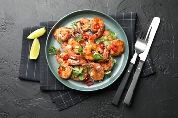 Tasty grilled shrimps with herbs and spices served on black table, flat lay. Delicious seafood dish