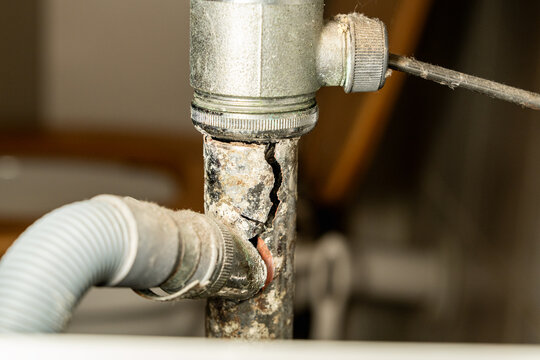 Broken drain pipe under bathroom sink, leaking water. Plumbing problem, home maintenance or emergency repair situation. Concept for household damage, insurance, plumbing services