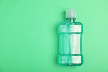 Bottle of mouthwash on green background, top view. Space for text