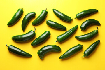 Green jalapeno peppers on yellow background, flat lay