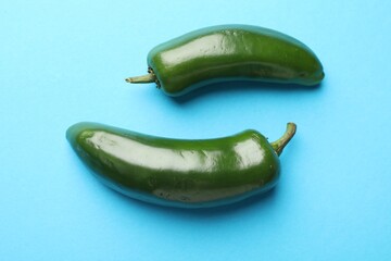 Green jalapeno peppers on light blue background, flat lay