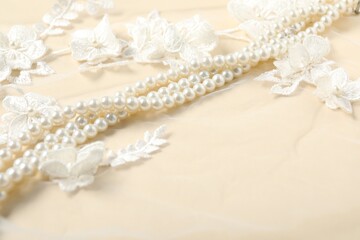 Beautiful pearl necklace on lace fabric, closeup