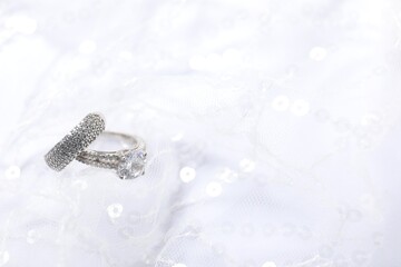 Beautiful rings on lace fabric with sequins, closeup. Space for text