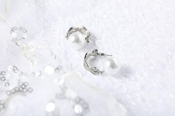 Beautiful pearl earrings on lace fabric, closeup