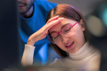 Asian programmers collaborating on software development at night, focused on writing code across multiple monitors in a tech office environment Programmers Collaborating on Software Development