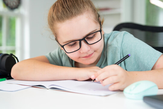 Kid using laptop for online studying at home. Child sitting at desk with laptop on virtual school lesson. Child learning with laptop. Young student . Kids watch online class on laptop. - Powered by Adobe
