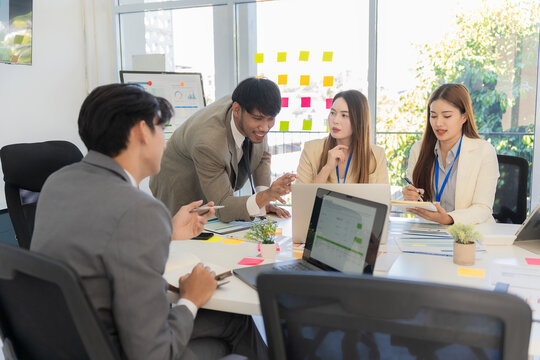 Marketing concept with laptop in office, Asian business group teamwork brainstorming meeting and discussing strategy, financial analysis, successful plan.