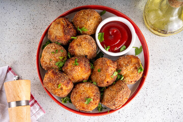 Homemade tasty airfryer made fish patties. Big plate of hot fish cutlets, with crispy crust, fried without oil. Healthy balanced food, high protein source recipe, with ketchup sauce on white table