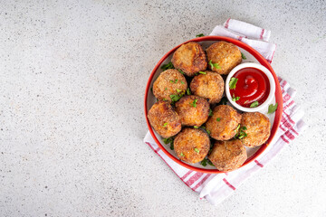 Homemade tasty airfryer made fish patties. Big plate of hot fish cutlets, with crispy crust, fried without oil. Healthy balanced food, high protein source recipe, with ketchup sauce on white table