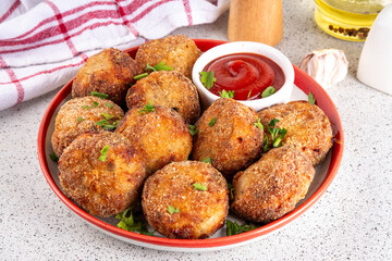 Homemade tasty airfryer made fish patties. Big plate of hot fish cutlets, with crispy crust, fried without oil. Healthy balanced food, high protein source recipe, with ketchup sauce on white table