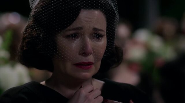 A cinematic close-up of a weeping, grieving middle-aged widow, in a black dress and a net veil over her face, at her husband's funeral, a dramatic advertising style with emotional realism