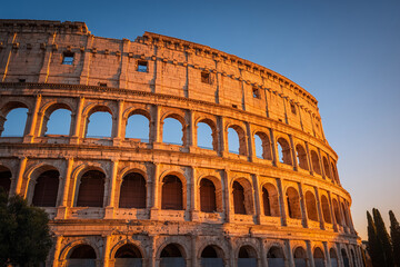 Fototapeta premium Colosseum captured at sunrise with golden sunlight reflecting on ancient stone arches, iconic Rome travel landmark photo.jpeg